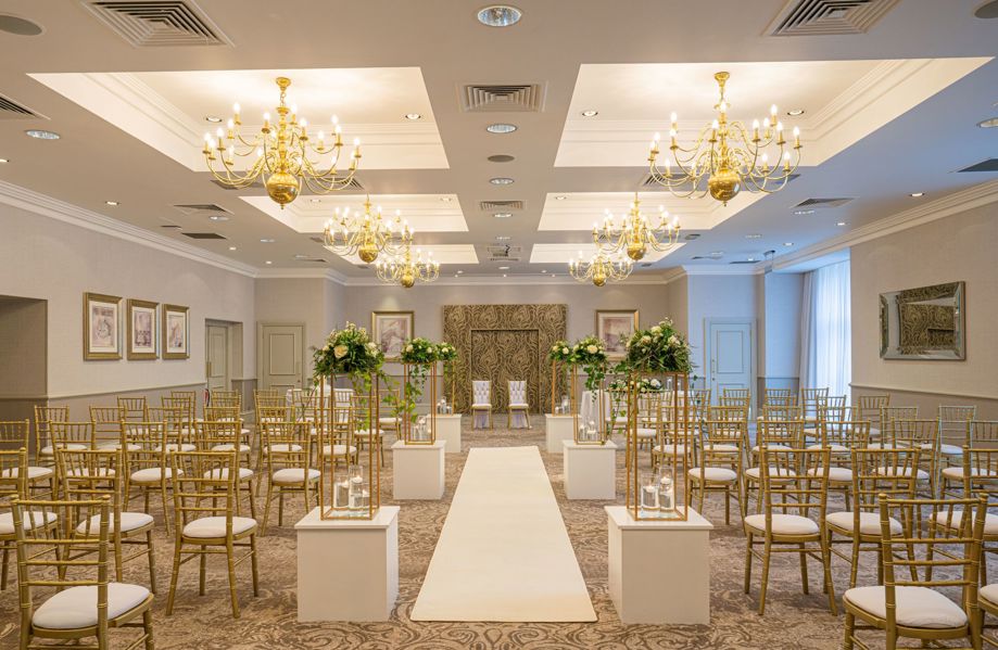 room set up for wedding ceremony with rows of Chiavari chairs and a white runner down to the aisle