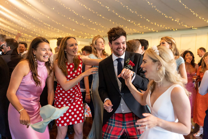 Bride and groom smile with friends on the dance floor