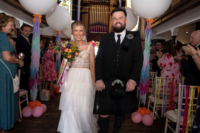 Couple walk hand in hand up the aisle