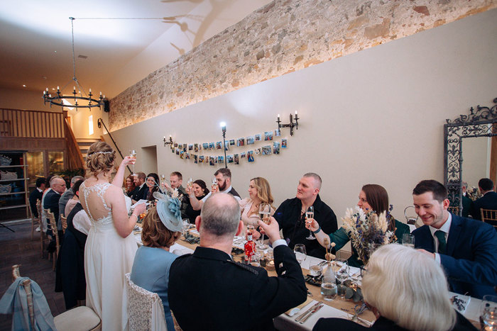 Bride making a toast amongst guests at wedding dinner