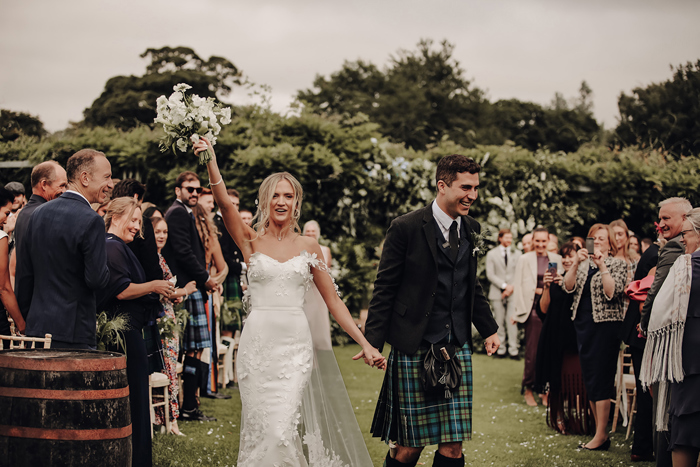 A Bride And Groom Walking Up Outdoor Aisle In Grounds Of Winton Castle