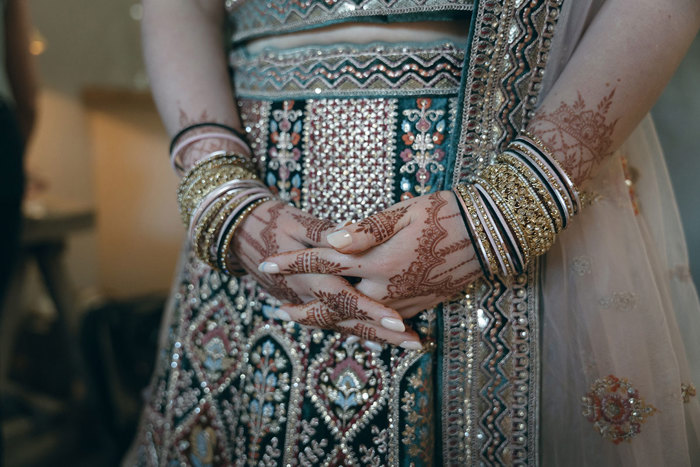 A person wearing a sari and henna tattoo on her hands.