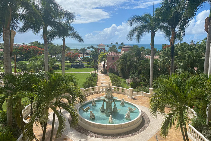 beachside Sandals resort with palm trees and a large stone fountain