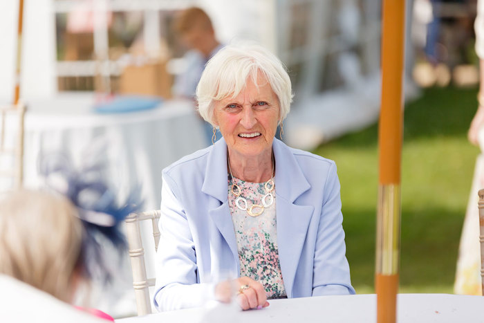 An elderly woman in a blue blazer and floral top