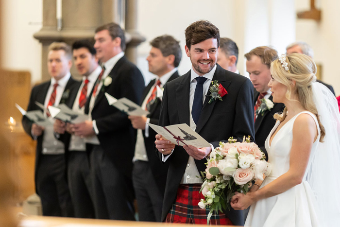 Bride and groom share music sheet at the top of the aisle