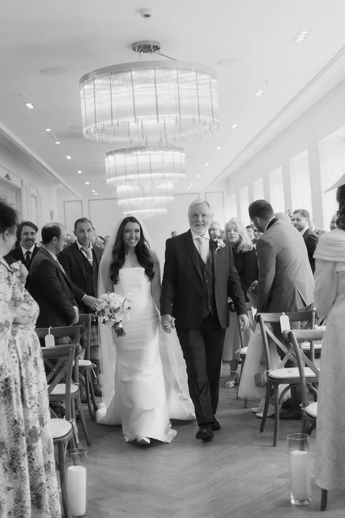 A bride and her father walking up the aisle together 