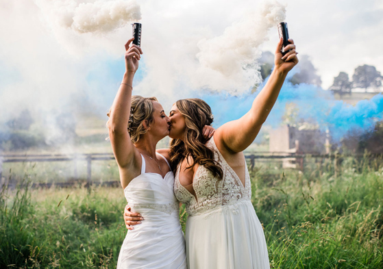 Brides hold smoke bombs during couple portraits