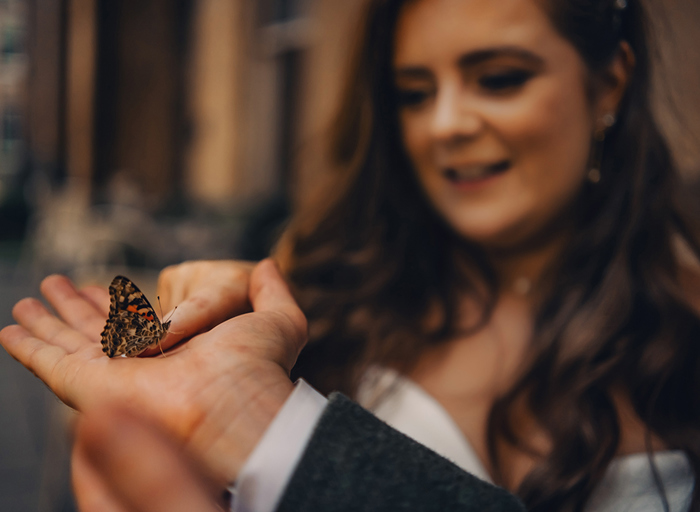 bride and groom holding and looking at real butterfly