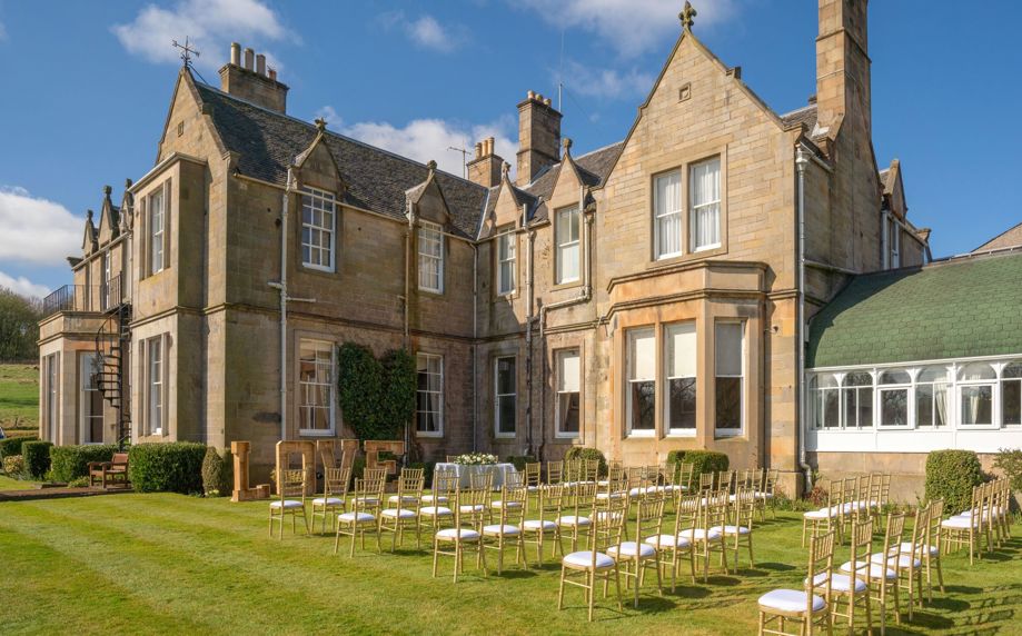 Exterior of Norton House Hotel Edinburgh with the lawn set up for a wedding ceremony with chairs and LOVE light up letters