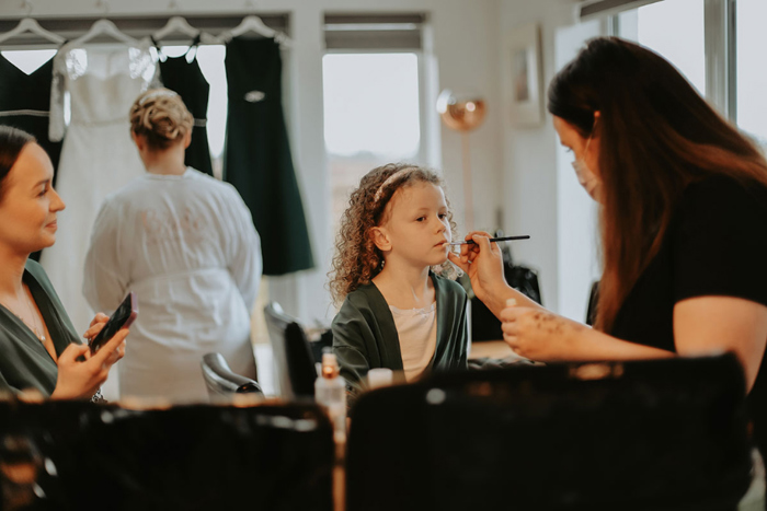 Flower girl has lipstick put on by professional