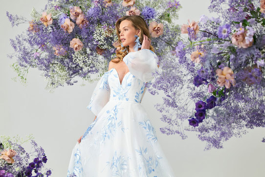 bridal model wears an off the shoulder puff sleeve gown covered in painted blue florals