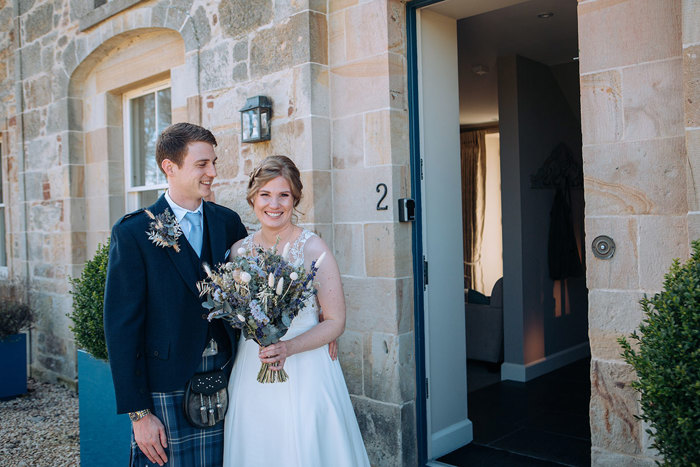 Bride and groom pose after their ceremony outside Newhall Mains