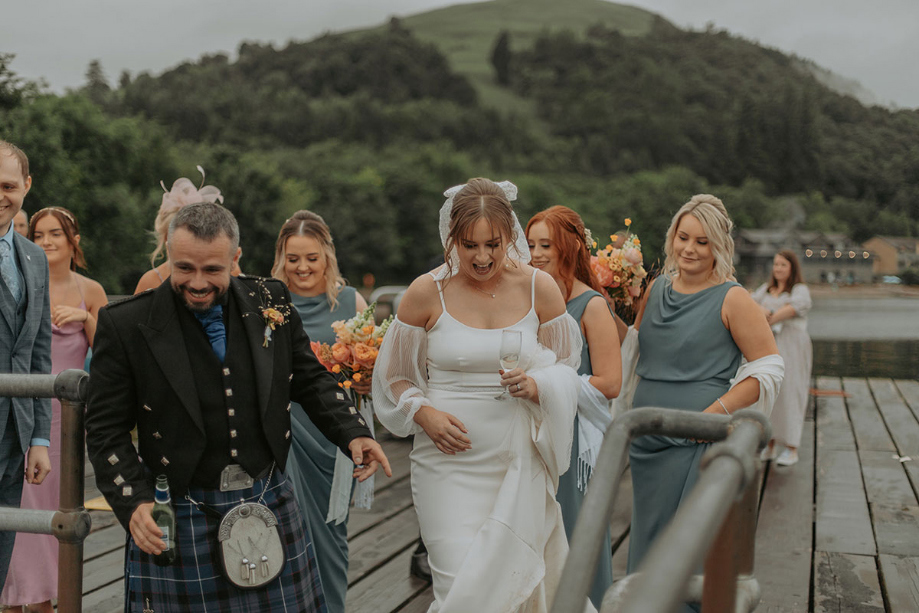 Bride and groom going on boat followed by guests