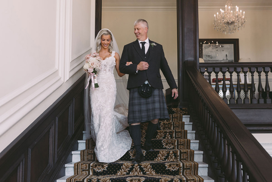 Bride and her father walk downstairs 