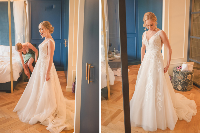 A bride standing in a long flowing wedding dress with floral applique, a deep neckline and thin straps 