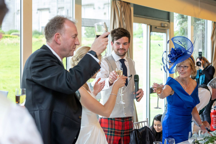 Bride, groom and family members raise their glasses in a toast