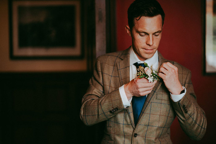 groom puts on flower buttonhole 