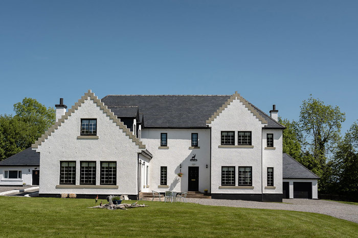 A large white house with a lawn. One of the Mini Manors on Achnagairn Estate.