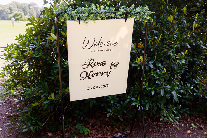 A welcome sign hanging in front of a bush