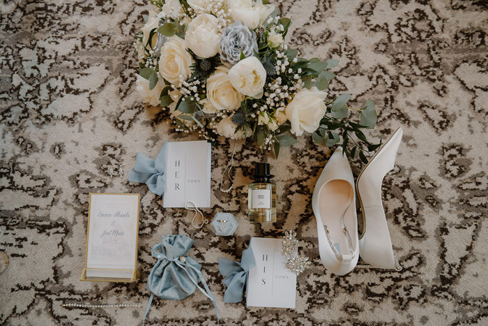 detailed shot of bride's items such as wedding shoes, vow book, jewellery and perfume