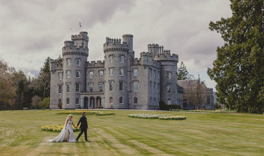 A bride and groom in front of a castle.