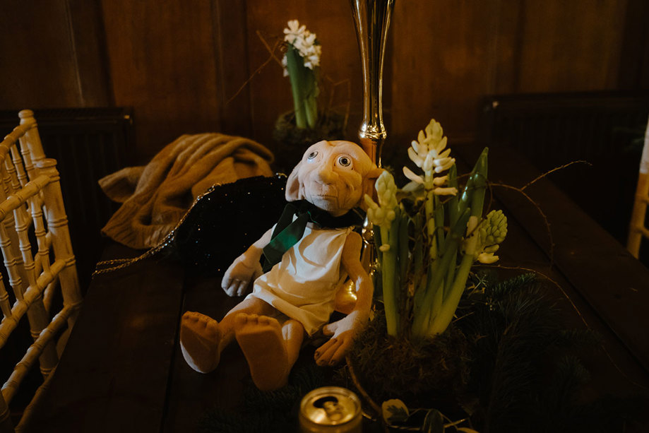 a Dobby stuffed toy sitting on a table next to a bunch of flowers.