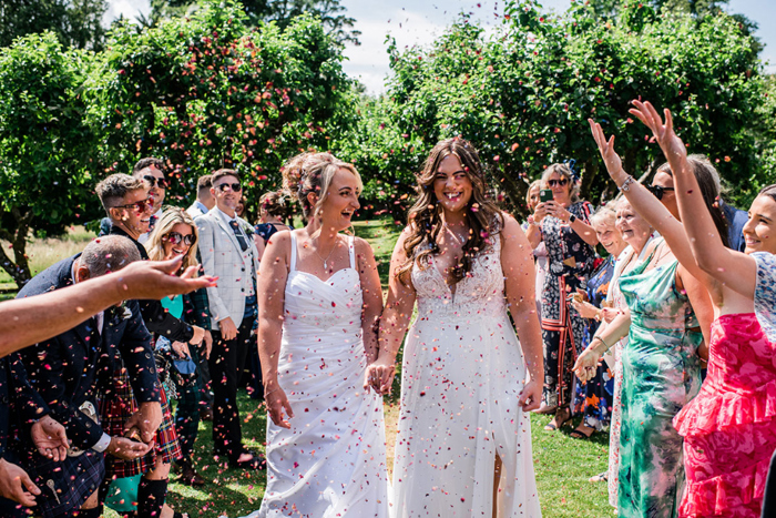 Two brides walk through confetti shower