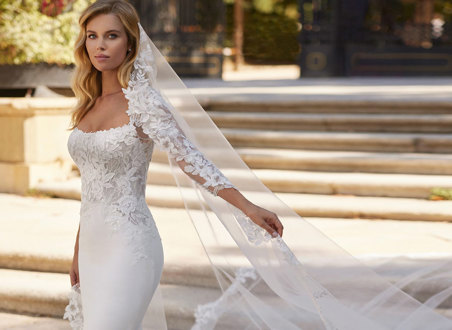 woman wearing long trailing mermaid wedding dress complete with matching veil