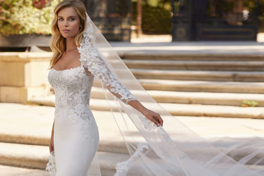 woman wearing long trailing mermaid wedding dress complete with matching veil