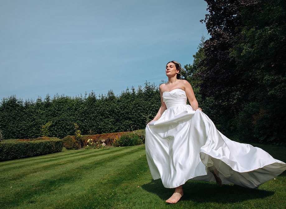 bride in strapless wedding dress running barefoot across grass