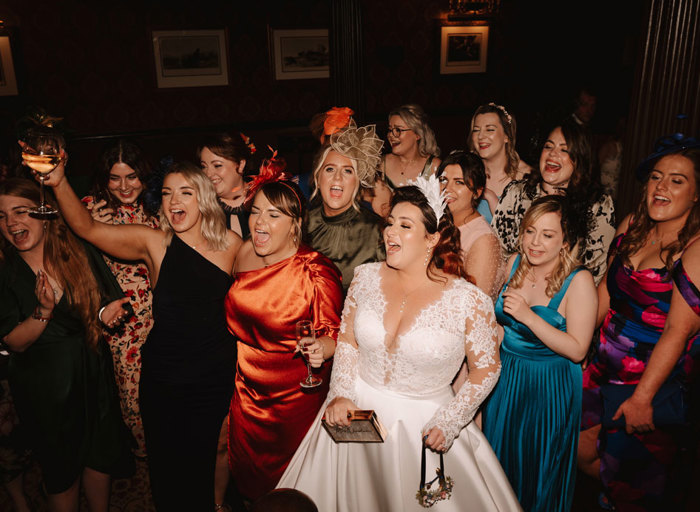 a group of women in colourful dresses singing on a dancefloor