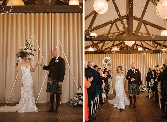 a bride and groom cheers with shot glasses standing in front of cream curtains and a triangular decorative ceremony arch with flowers on left. A joyous bride and groom walk up the aisle with rows of wedding guests clapping either side