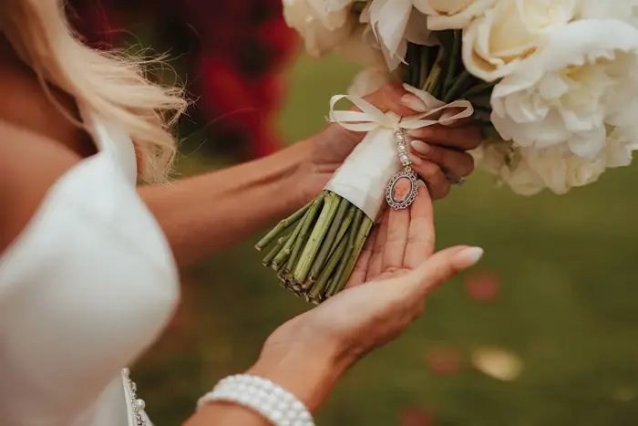 bride holding bouquet looking at photo of lost loved one