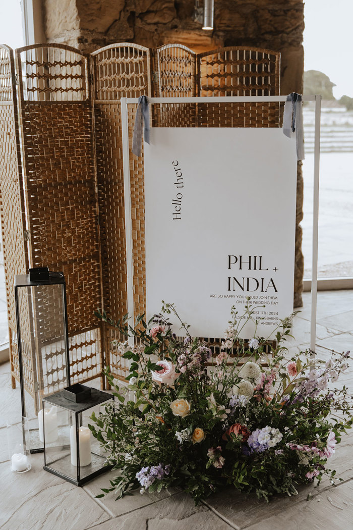 white wedding welcome sign with pastel flowers in front