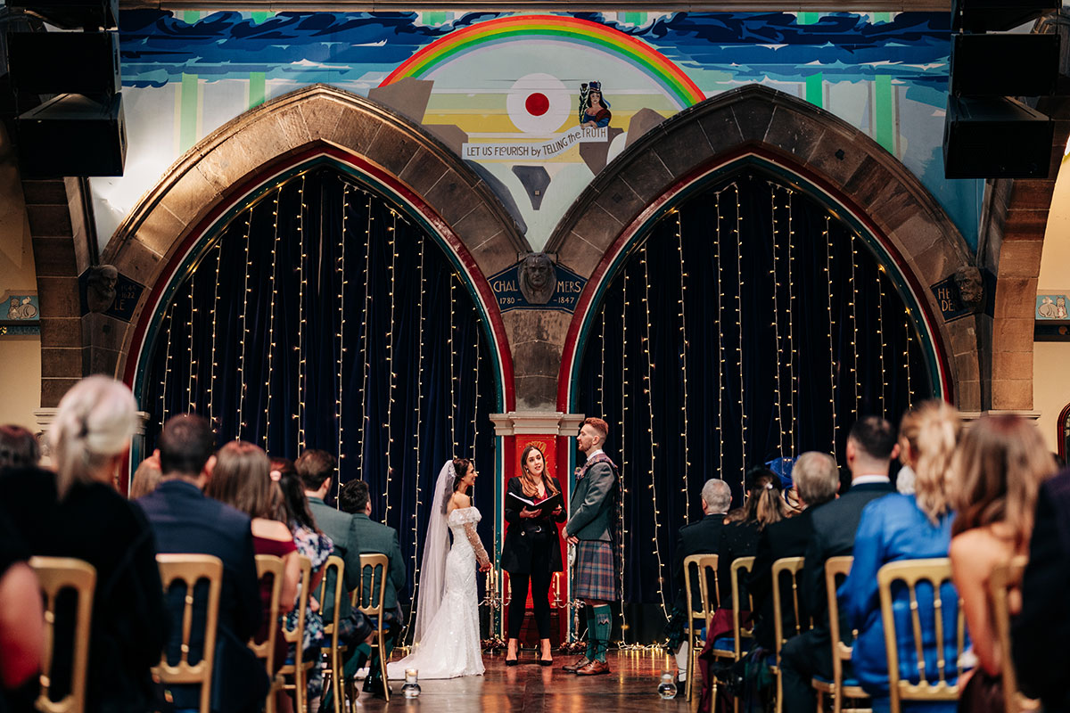 bride and groom stand facing one another during wedding ceremony at oran mor