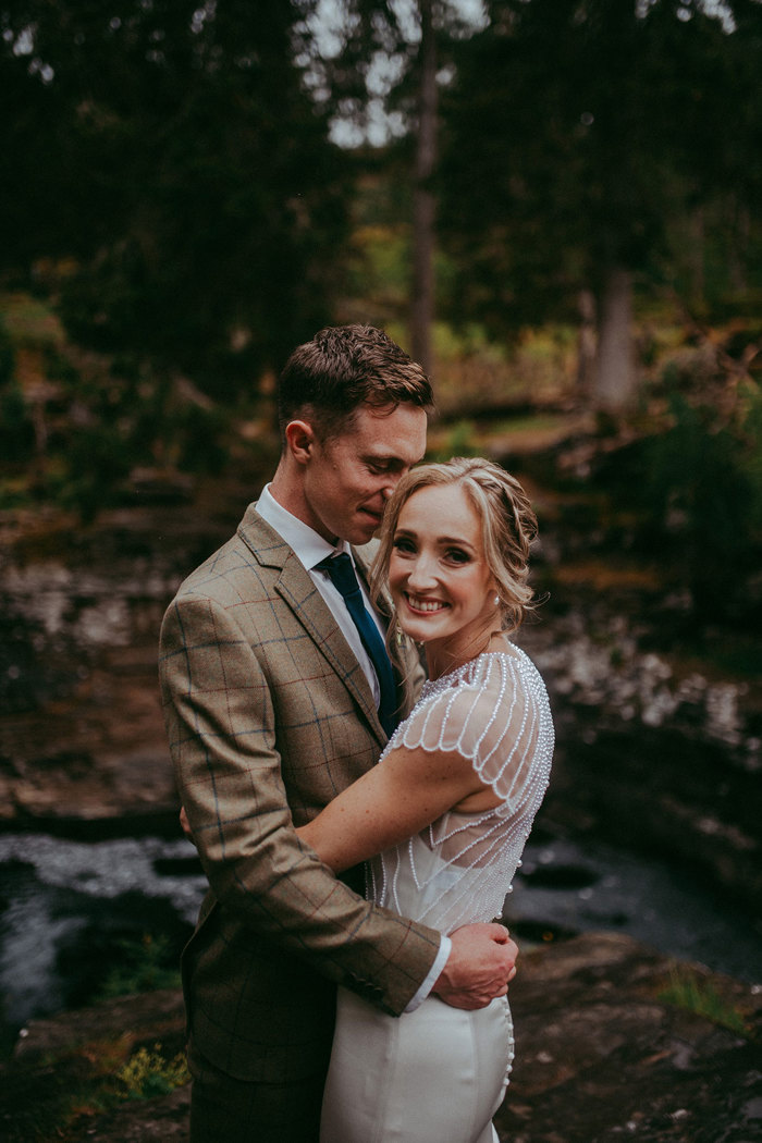 bride looking towards camera while hugging groom at mar lodge