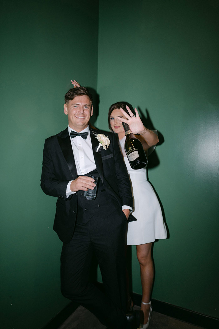 a bride and groom posing for a photo against a green wall at The Engine Works.