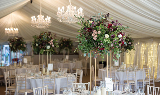 formal round table set ups feature elevated floral displays of dark reds and purples