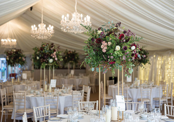 formal round table set ups feature elevated floral displays of dark reds and purples