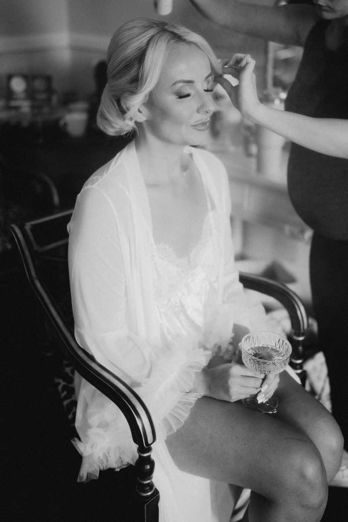 A woman wearing a low bun getting her makeup done 