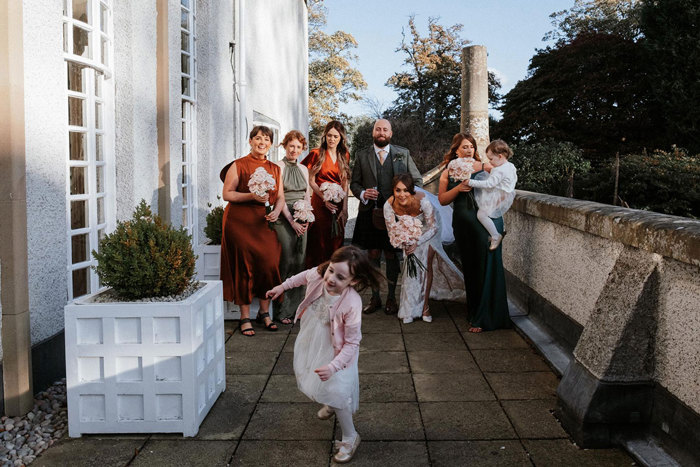 Wedding party standing on patio watching flower girl