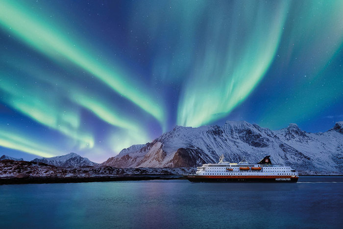 a ship sailing under the northern lights with snow covered mountains in the background