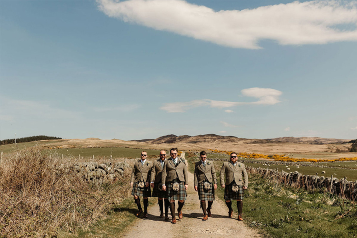 Groom and groomsmen walk down country road