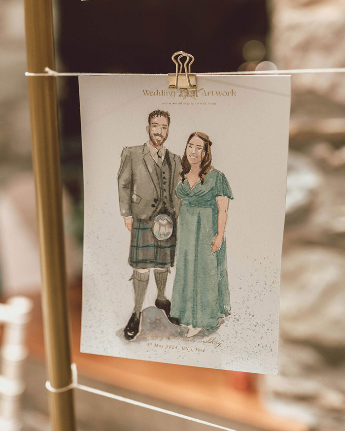 a watercolour painted card of a couple in formalwear is hung up on a string with a clip