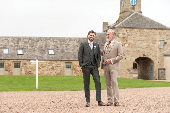 two men in Slater Menswear suits standing outside Rosebery Steading
