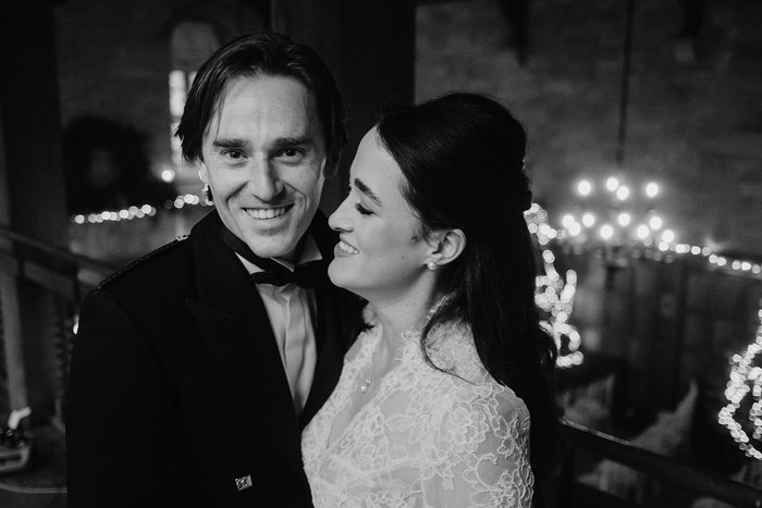 a bride and groom pose for a photo with soft illuminated lighting in background.