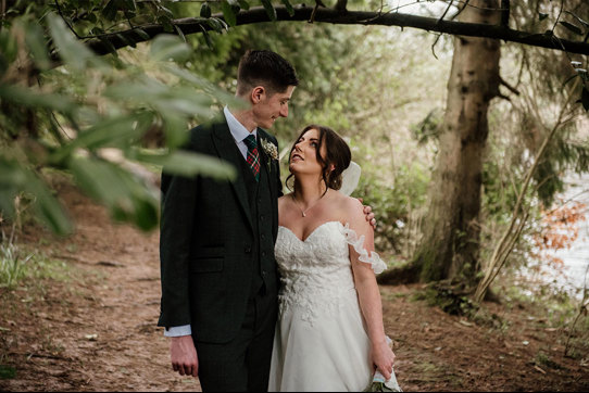 bride and groom looking at each other in a woodland