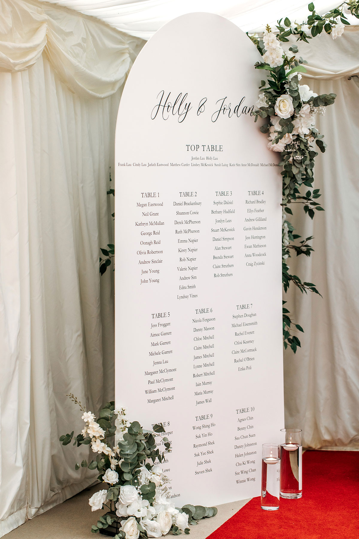 white table sign with guests names for wedding breakfast with white and green foliage around it