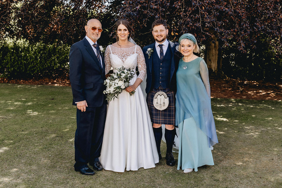 Bride and groom smile with groom's parents