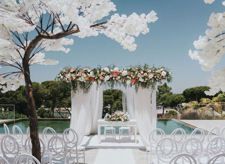 a white wedding ceremony set up outside with blossom trees at Quinta do Lago Portugal